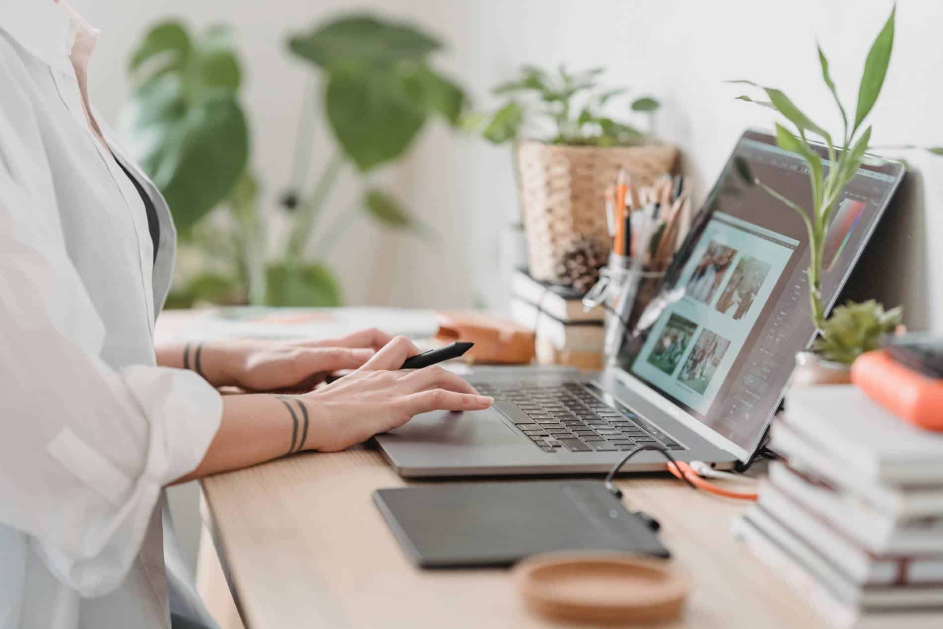 A person using a laptop computer to edit photos in photoshop.