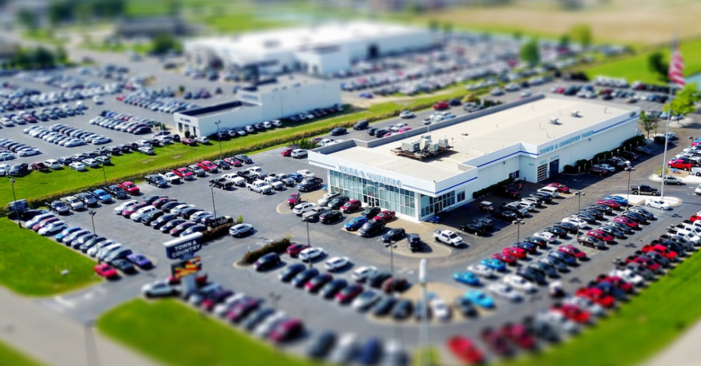 Stylized aerial view of car dealership with a full parking lot