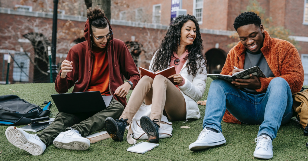 Cheerful students with books sitting near university