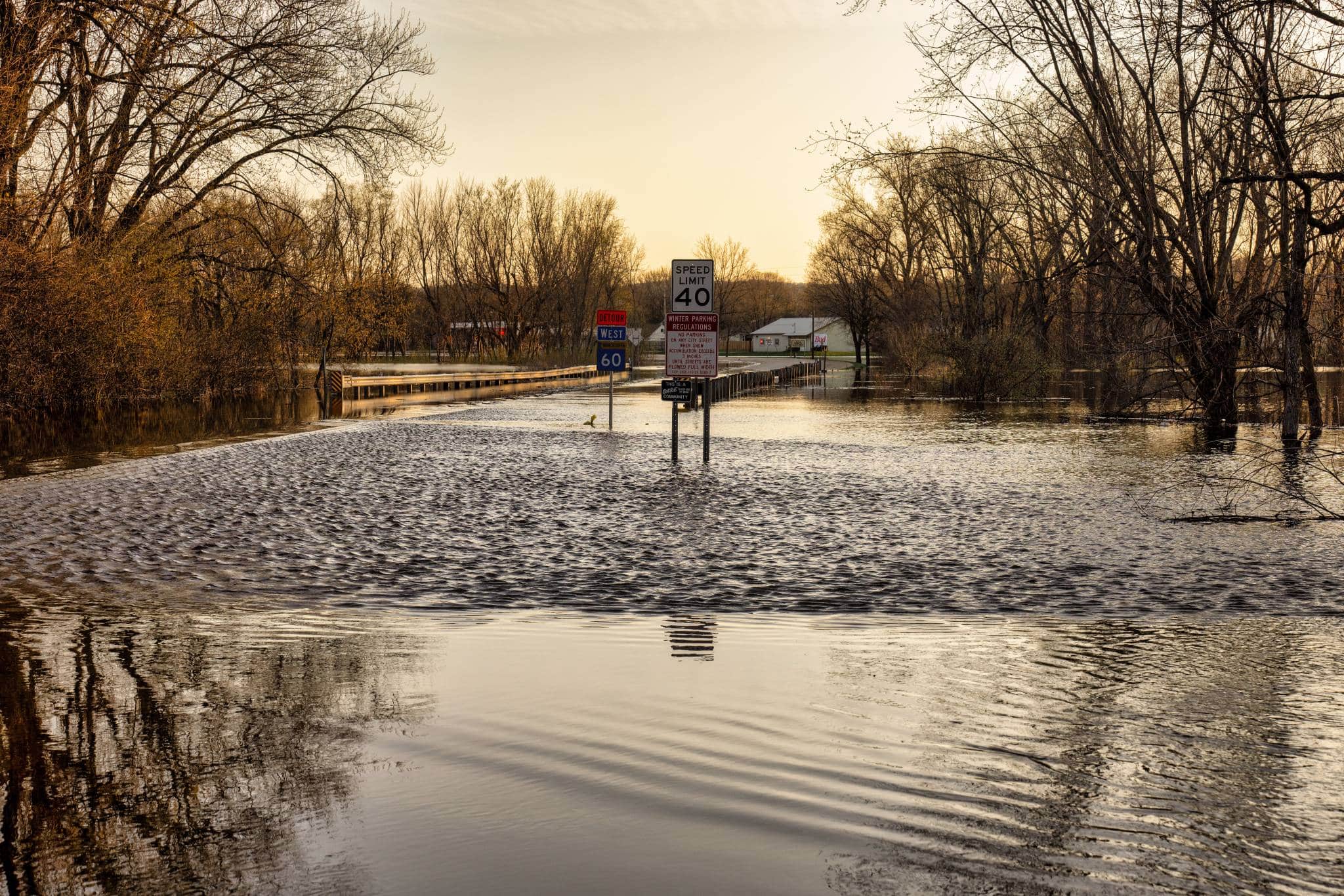 Road Flooded, Street signs are half in the water, sun is setting