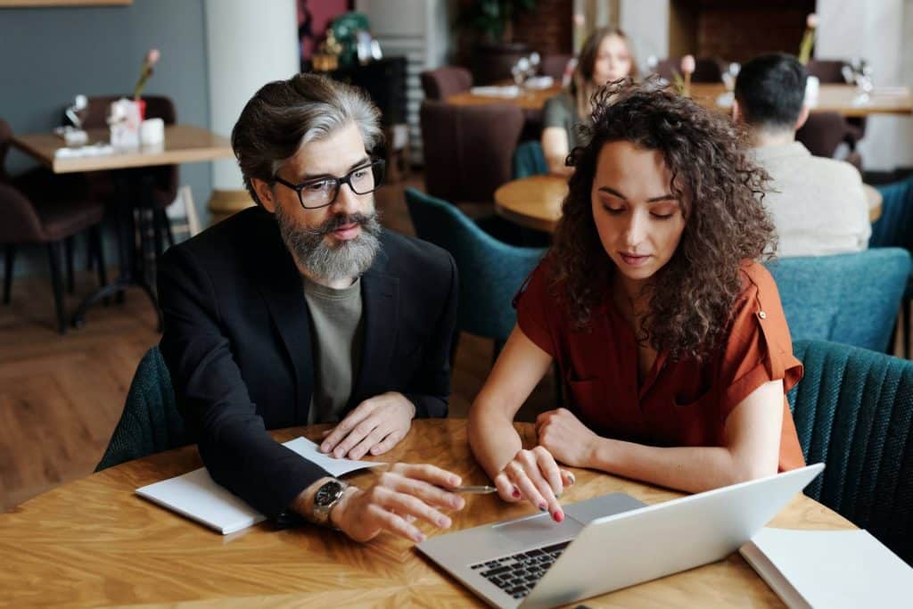 Two people sitting at a laptop working together on a content audit.