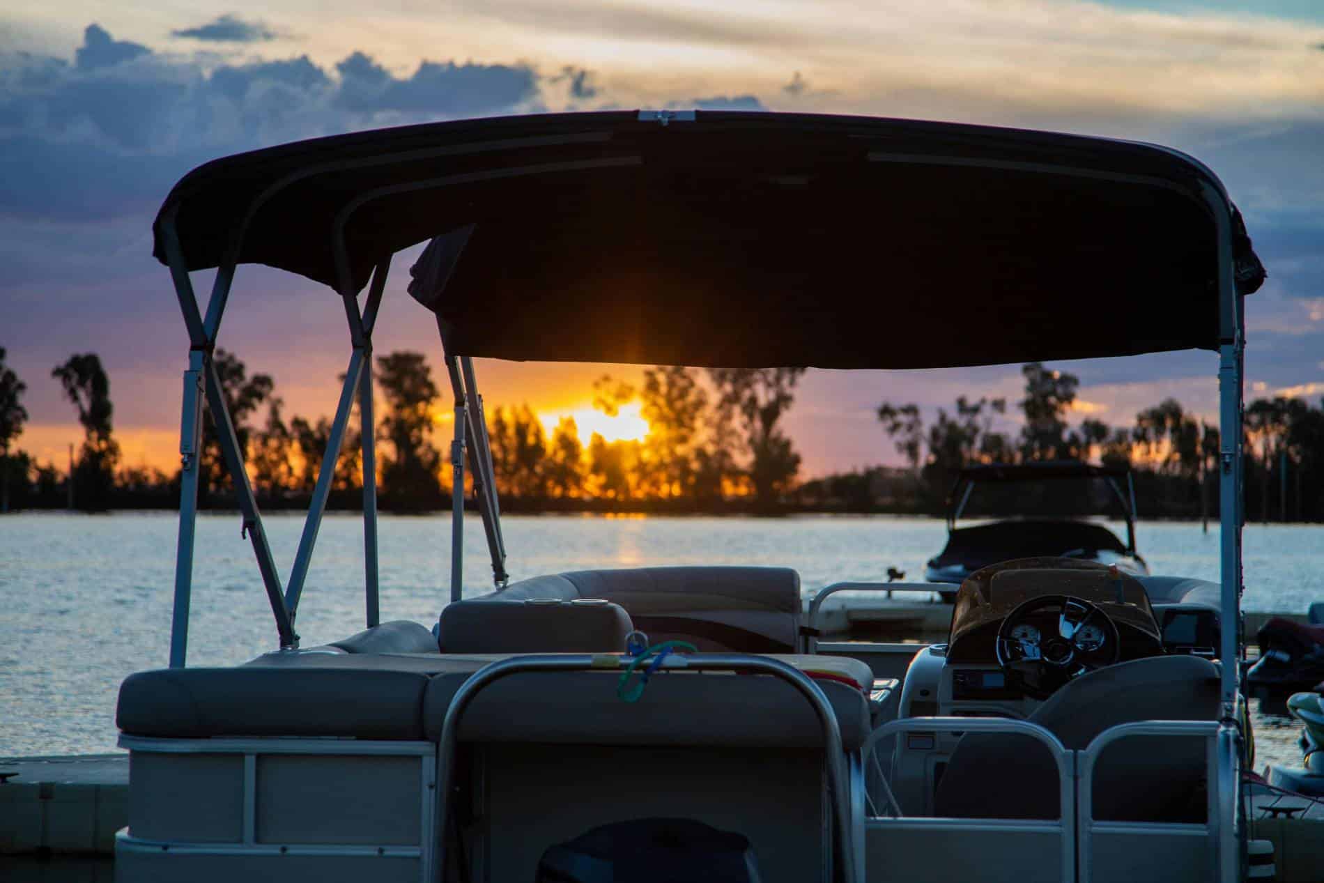 This image shows a pontoon boat from the rear, with a sunset on the horizon.